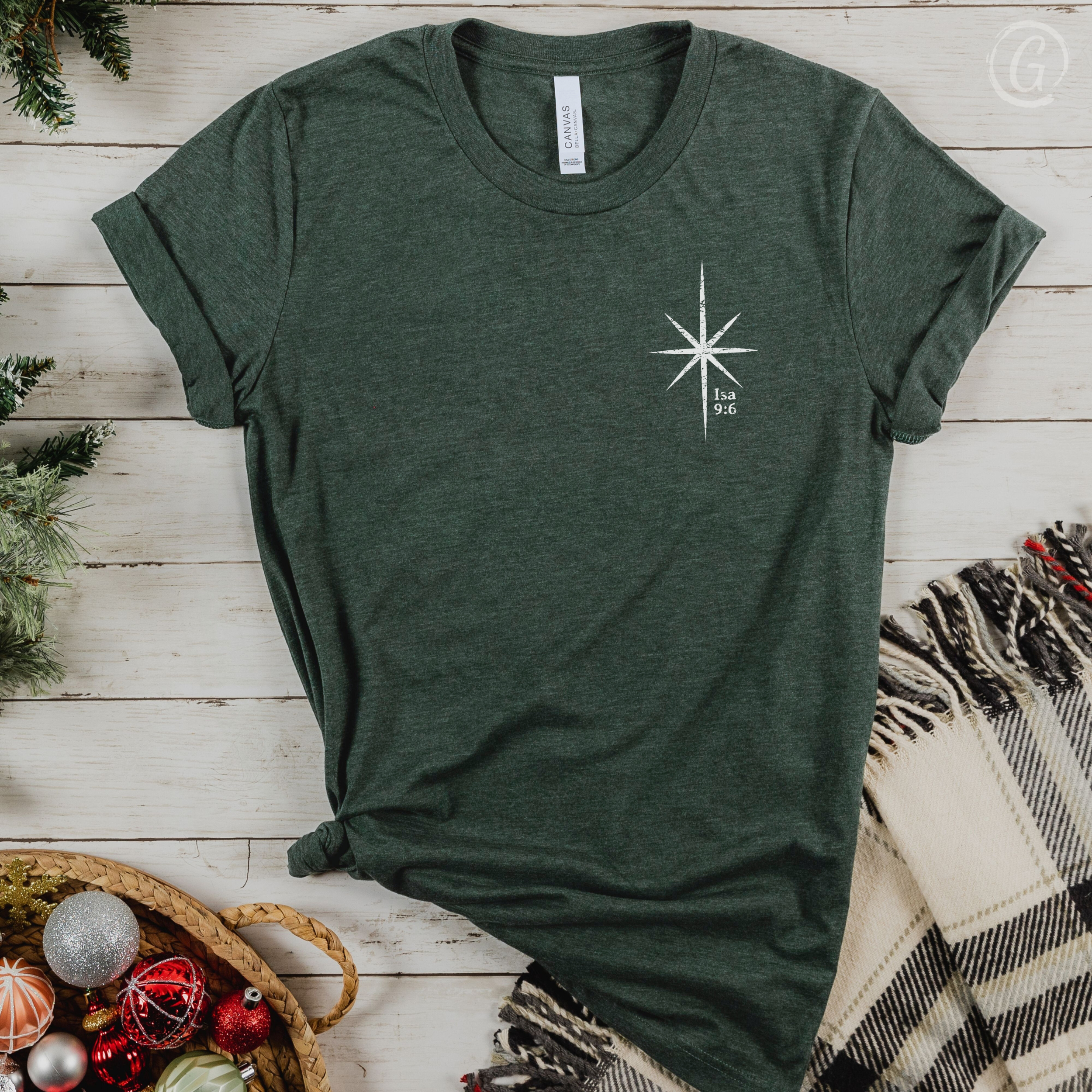 Green t-shirt with a white star design on a wooden surface with Christmas decorations.