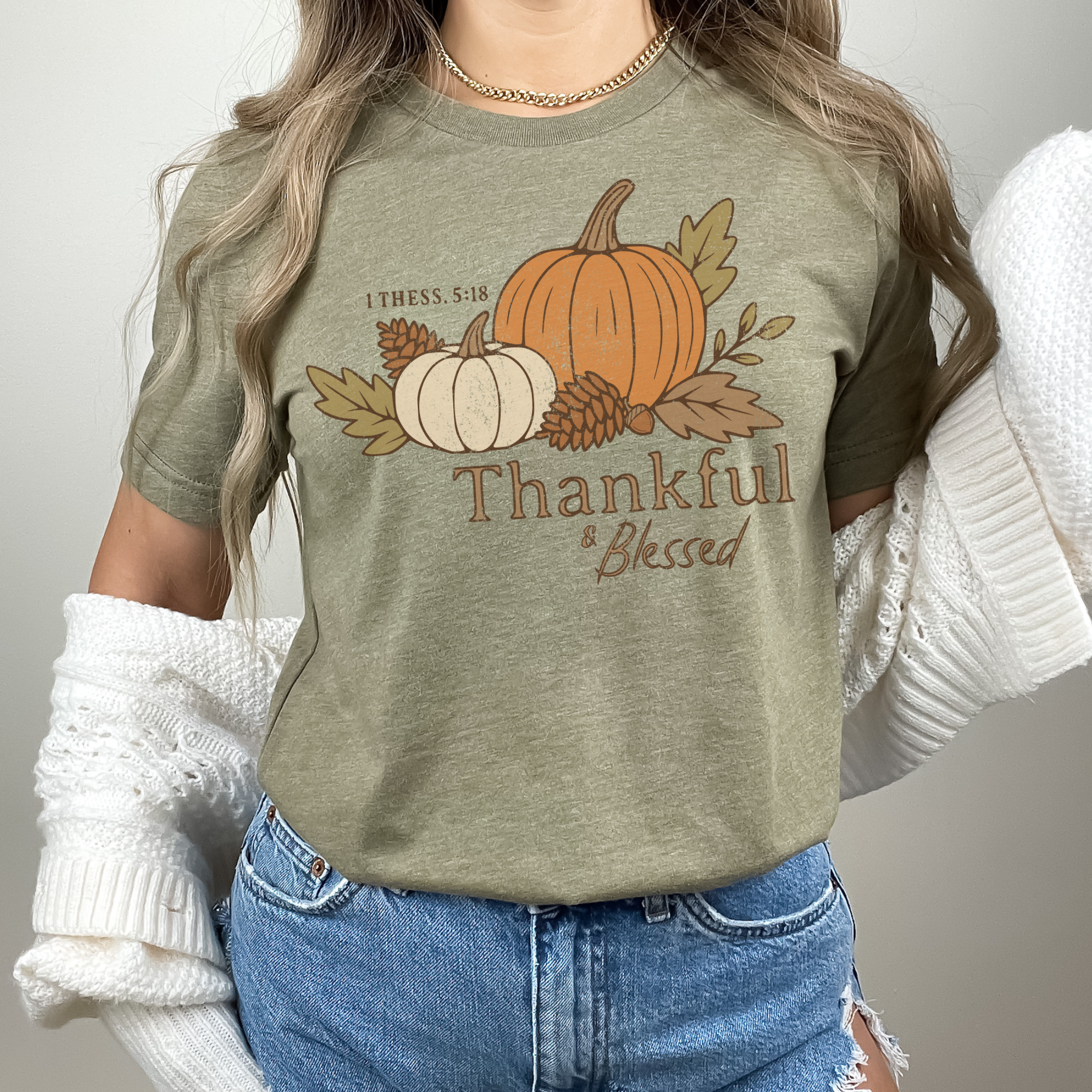 Person wearing a green t-shirt with a pumpkin and leaf design and text 'Thankful & Blessed'.