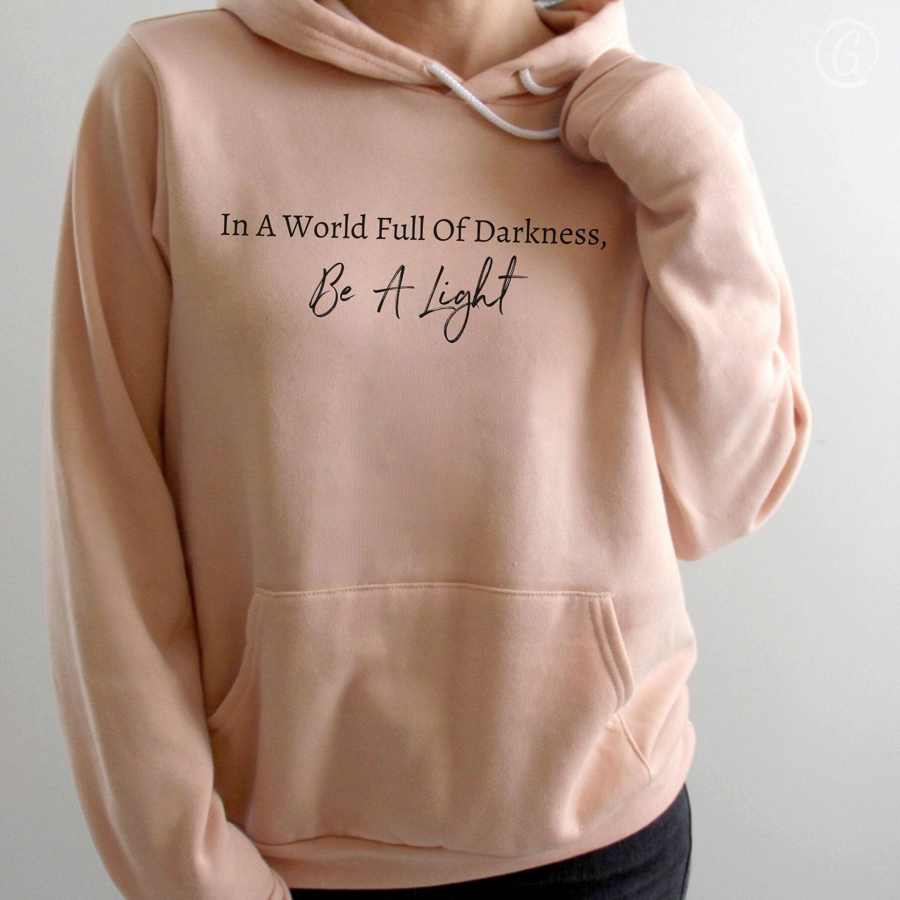 In A World Full Of Darkness, Be A Light Premium Unisex Pullover Hoodie Peach