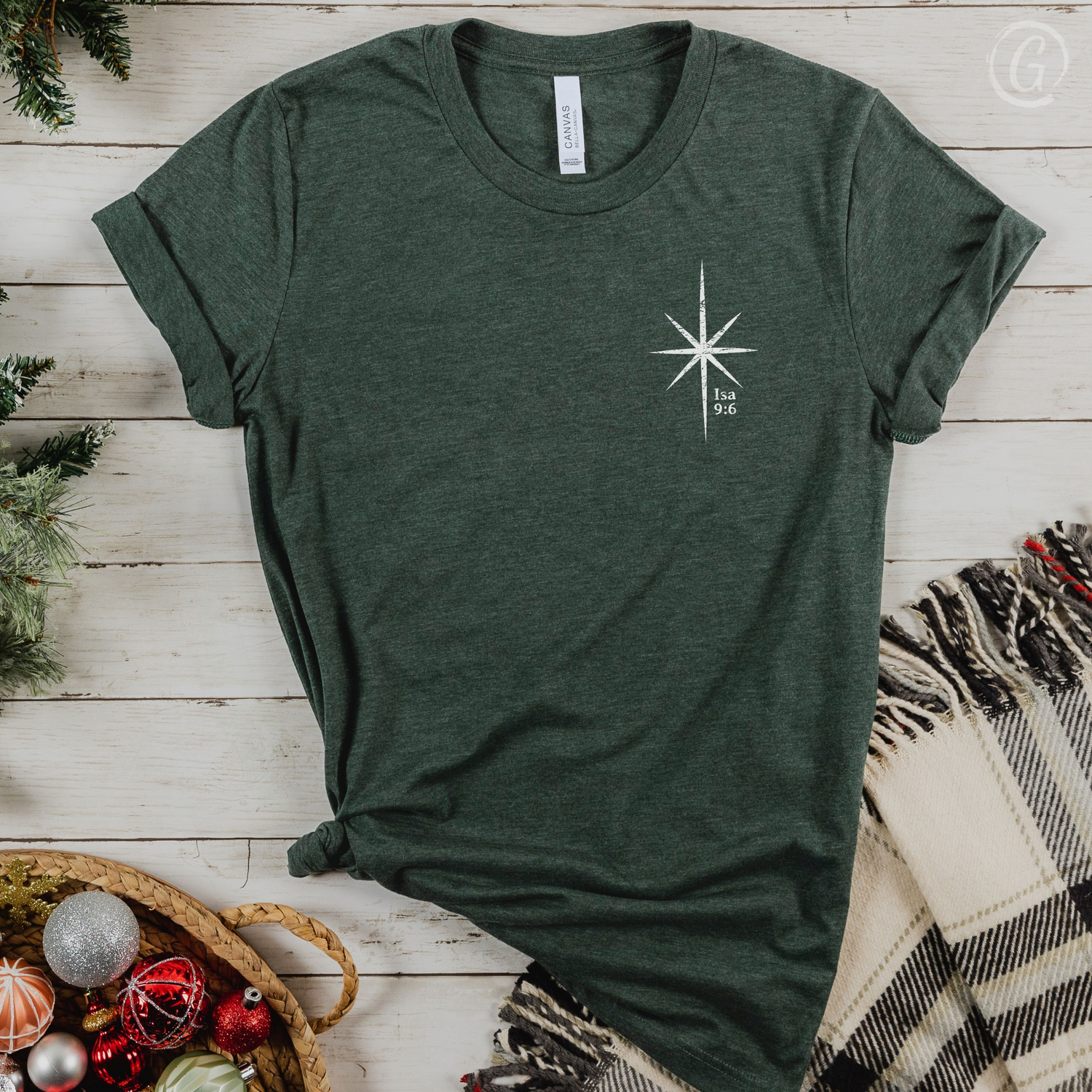 Green t-shirt with a white star design on a wooden surface with Christmas decorations.